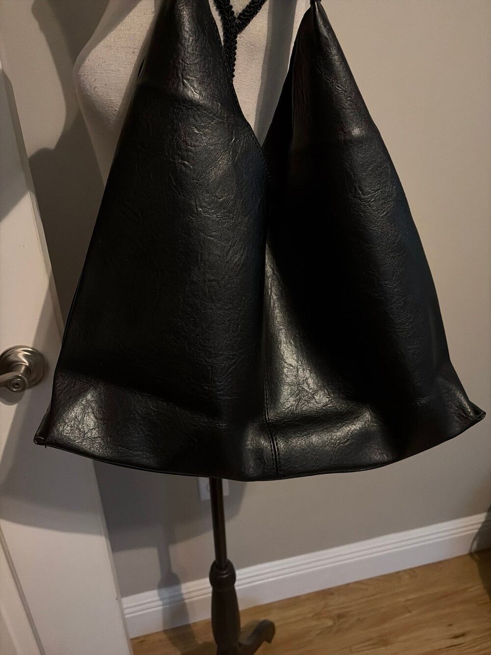 Black slouchy vegan leather shoulder bag with an unstructured, triangular hobo